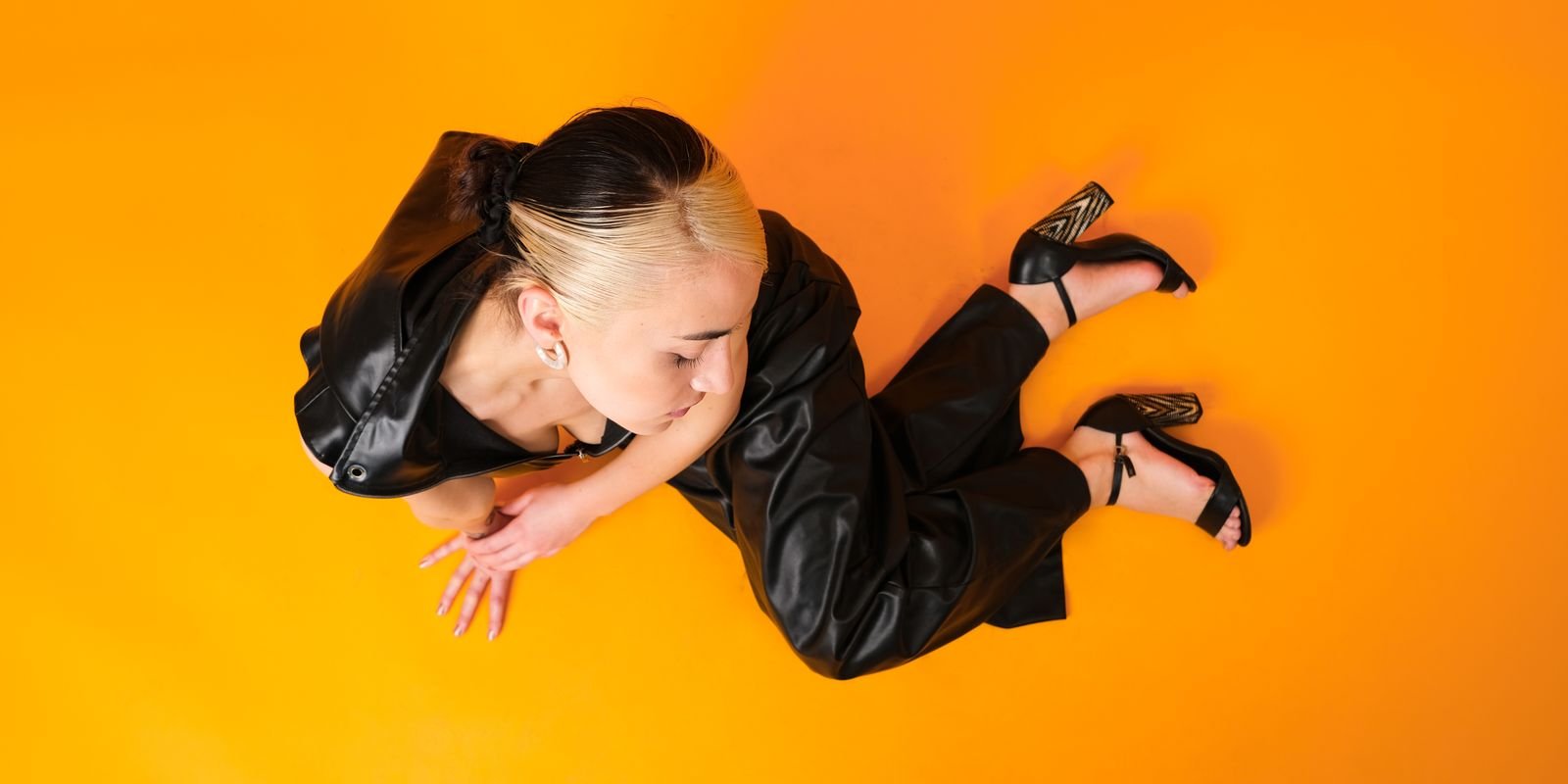 Ein Model in markantem schwarzem Leder vor kühnem Studiohintergrund